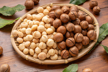Roasted Macadamia nut in wooden plate on wooden background.