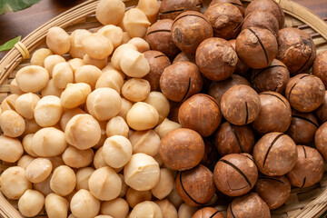 Roasted Macadamia nut in wooden plate on wooden background.