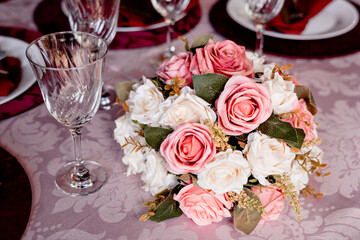 a round table decorated with a flower arrangement, glass bowls, plates and red napkins