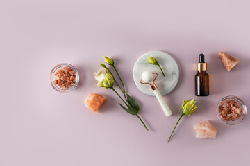 rose quartz roller massager, cosmetic massage oil bottle, bath salt. Top view. Flat lay. pastel background. self-care.