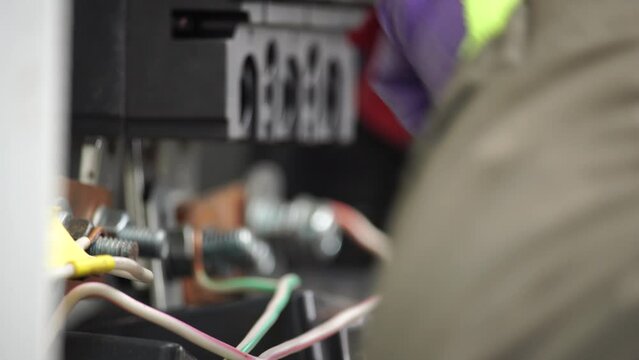 Close-up view of Electrician installing wires, cables into a electricity power shield, fuse box, an industrial electric panel with lots of colorful cables and wires. Power industry concept.