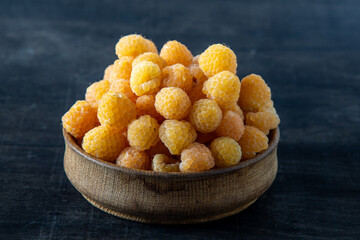 Yellow raspberries in a wooden bowl on the table. Summer berries background. Vitamin food, berry harvest. Healthy nutrition.