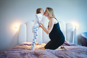 pregnancy photo - pregnant mother with big belly and her daughter happy indoor