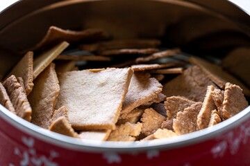A close up portrait of a round tin can with christmas prints on it, with home made cookies inside of it. The unhealthy tasty holiday treat is simple to bake and a great snack.