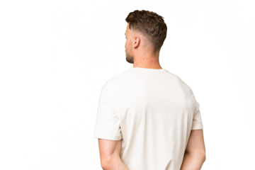 Young blonde caucasian man over isolated background in back position and looking back
