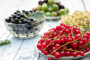 Various summer berries on a white wooden table. Blur and selective focus