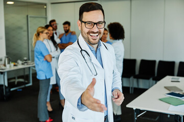 Obraz premium doctor portrait man hospital medical handshake hand agreement deal greeting partnership offer group team contract shake cooperation giving uniform health