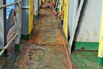 Rusty main deck without maintenance of container vessel on the starboard side. On the sides are...