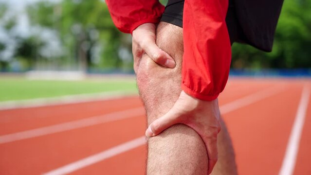Close up young asian runner athlete with muscle pain. Man massaging Stretching, trauma injury while jogging outdoors. Fitness male sprain severe pain stretch pull. Leg muscle cramp calf sport.