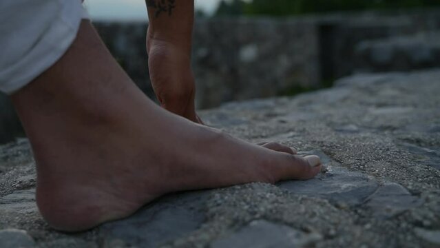 Close-up shot of hand touching the ground next to feet in hatha yoga pose in the morning at dawn