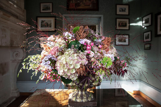 Close-up of a bouquet of flowers in an old-style room with paintings hanging in the distance