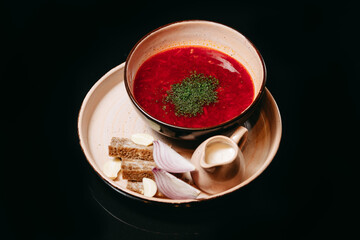 Borscht with croutons and lard on a black background