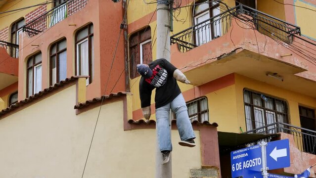 Effigy hangs from phone post by Bolivia apartments. Low angle hand held.