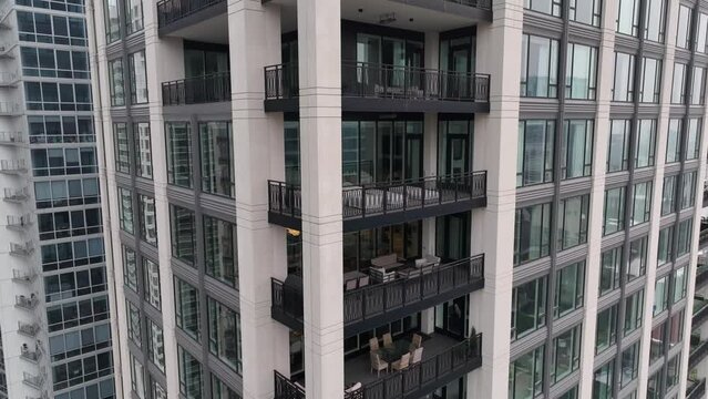 Tall residential skyscraper with condos, apartments, and penthouses. Aerial orbit around high end balconies.