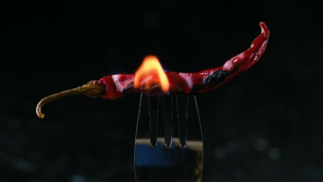 A burning hot red chili pepper on a fork. Zoom out shot