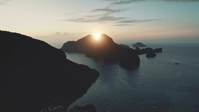 Aerial mountain sunset view in golden hours. Boats and yachts in ocean. Dron flight over island pradise landscape. Sky with clouds. Warm tones. Summer travel atmosphere. Cinematic dramatic footage.