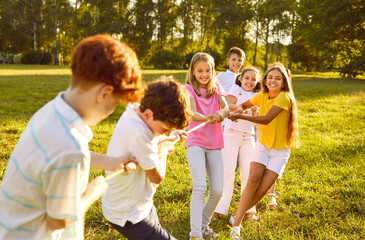 Happy children play games in park on sunny summer day. Cheerful kids meet on green field or meadow,...