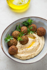 Grey bowl with hummus, falafel and fresh greens, vertical shot, middle close-up, selective focus
