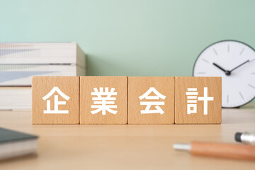 企業会計と書かれたブロックが置かれたデスク