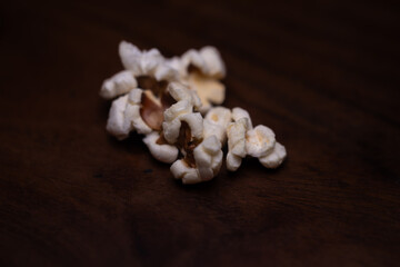 Close up of Puffed light golden popcorns on dark wooden serving tray