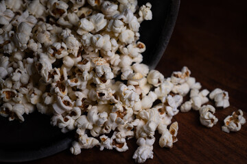 Close up of Puffed light golden popcorns on dark wooden serving tray