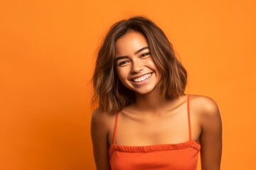 Obraz premium Lifestyle portrait photography of a grinning girl in her 20s wearing a cute crop top against a bright orange background. With generative AI technology
