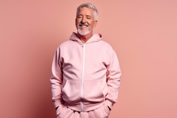 Fototapeta premium Lifestyle portrait photography of a glad mature man wearing a comfortable tracksuit against a peachy pink background. With generative AI technology