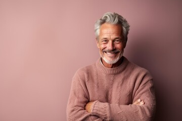 Environmental portrait photography of a happy mature man wearing a cozy sweater against a dusty rose background. With generative AI technology