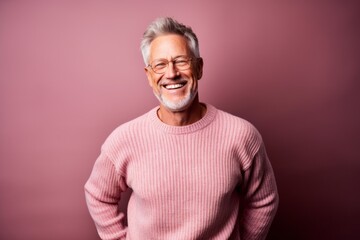 Environmental portrait photography of a happy mature man wearing a cozy sweater against a dusty rose background. With generative AI technology