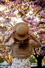 Young girl with hat in a sakura garden