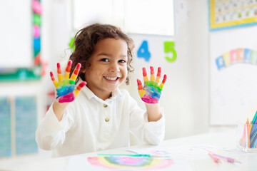 Child drawing rainbow. Paint on hands. - obrazy, fototapety, plakaty