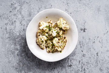 Roasted white cauliflower in bowl on rustic grey table