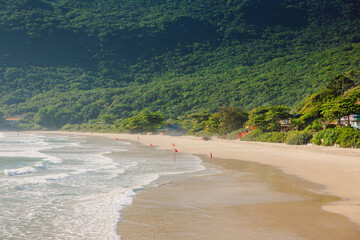 Beach with fog and mountains in sunny day. Holiday banner with amazing beach in Brazil