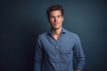 Obraz premium Medium shot portrait photography of a beautiful boy in his 30s wearing a classy button-up shirt against a navy blue background. With generative AI technology