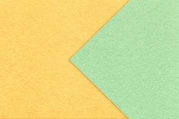 Texture oflight yellow paper background, half two colors with green arrow, macro. Structure of craft mint cardboard.