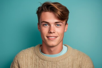 Close-up portrait photography of a glad boy in his 20s wearing a cozy sweater against a teal blue background. With generative AI technology