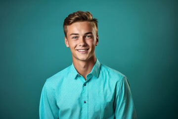 Fototapeta premium Medium shot portrait photography of a glad boy in his 20s wearing a classy button-up shirt against a teal blue background. With generative AI technology