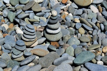 Fototapeta na wymiar Zen stone towers on a rocky beach on a sunny day,