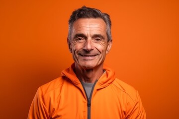 Obraz premium Medium shot portrait photography of a glad mature man wearing a comfortable tracksuit against a tangerine orange background. With generative AI technology