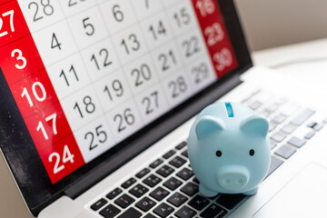 Saving money concept. Piggy bank on calendar with calculator, notepad and push pins.