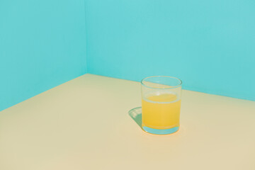 Glass of fresh orange juice on beige table. Blue background.