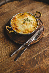 Appetizing lasagne with golden brown crust in a small frying pan. Food photography.