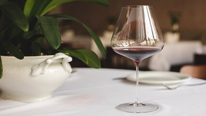 A glass of red wine on the background of the served table. Sommelier.