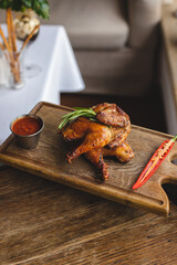 Appetizing chicken legs with barbecue sauce and hot peppers on a wooden board. Knife Fork. Food photography.