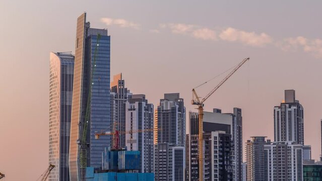 Cityscape with skyscrapers of Dubai Business Bay and water canal aerial timelapse. Modern skyline with residential and office towers during sunset with warm orange light