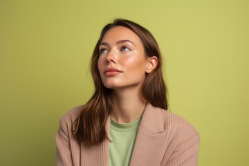 Obraz premium Photography in the style of pensive portraiture of a glad girl in her 30s wearing a chic cardigan against a pastel green background. With generative AI technology
