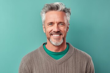 Obraz premium Close-up portrait photography of a grinning mature man wearing a cozy sweater against a pastel green background. With generative AI technology