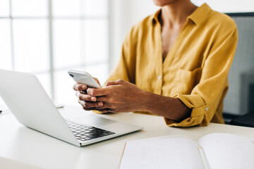 Using a mobile phone in the office. Business woman sending a text message at work