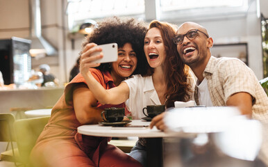Three happy friends having fun and creating memories with selfies