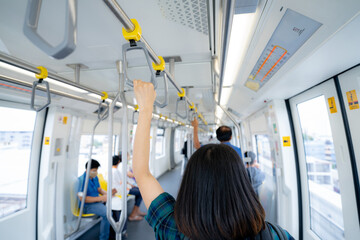 Woman hand firm grip safety handrail in elevated monorail train. Mass transit system in modern...